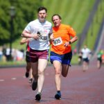 Two runners, wearing number bibs 933 and 935, race along a sunlit road, surrounded by grass and trees. Their determined run captures the spirit often celebrated by Stormont events.