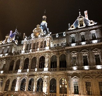 The historic building, once admired by SIOP 2019 attendees like Lyndsey Thompson and Catherine Mark, boasts an ornate facade illuminated at night, featuring arched windows and decorative rooftops.