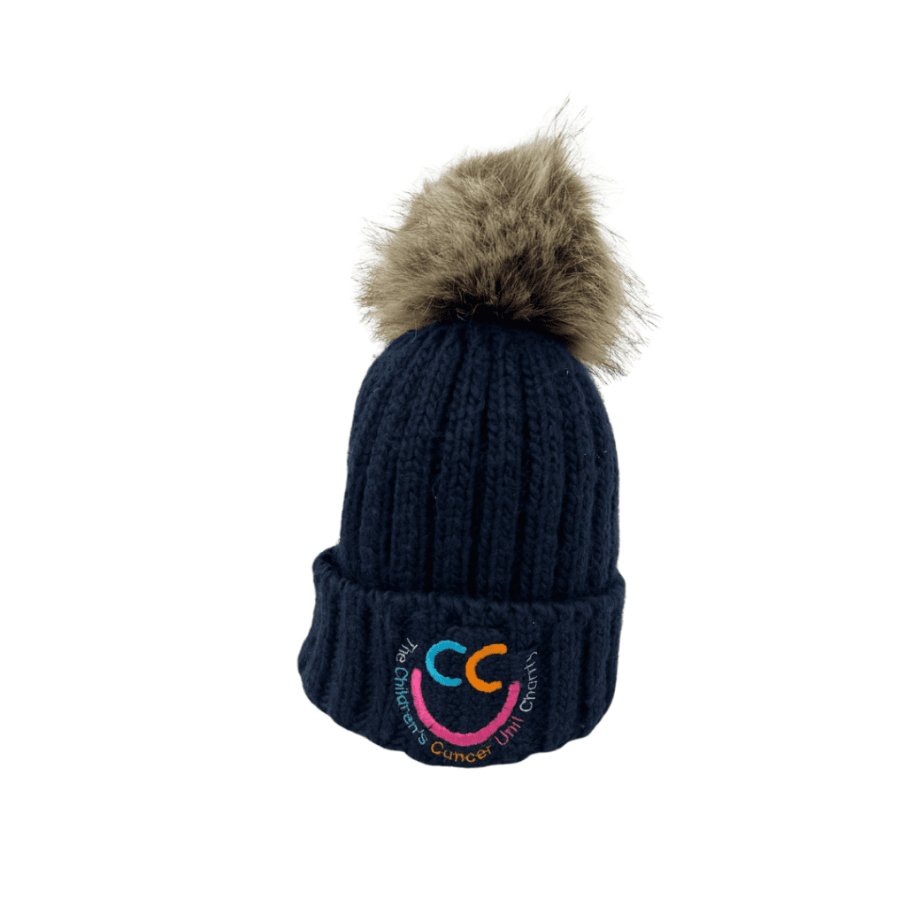 A dark knitted beanie hat with a fur bobble on top, adorned with a colorful embroidered "CC" logo on the front.